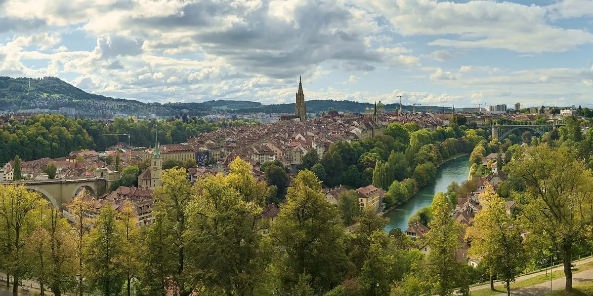 Bern's old town seen from the Rosengarten: red roofs and the minster's spire above the River Aare, among autumn trees